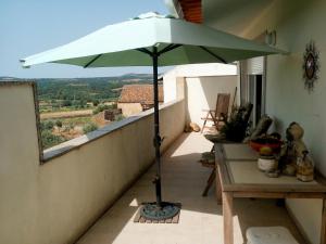 einen grünen Sonnenschirm auf einem Balkon mit einem Tisch in der Unterkunft Retiro Terrasol in Tó