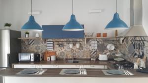 een keuken met blauwe hanglampen boven een aanrecht bij a Casa di Ele in Napels
