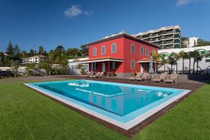 フンシャルにあるCentury House with private pool by HR Madeiraの赤い建物の前の大きなスイミングプール