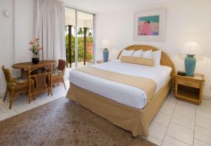 Aston Maui Kaanapali Villas في لاهينا: غرفة نوم بسرير كبير وطاولة وكراسي