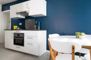 a kitchen with white cabinets and a table and a blue wall at Apartments Brussels Airport in Zaventem