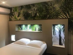 - une chambre avec un lit et une peinture d'un palmier dans l'établissement L'Olivine, à Saint-Pierre