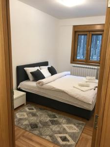 a bedroom with a bed with white sheets and a window at Zlatibor apartmani Jakovljevic in Zlatibor