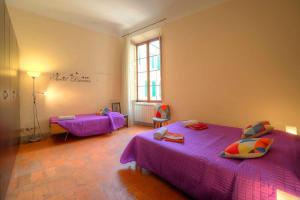 Cette chambre comprend 2 lits avec des draps violets. dans l'établissement Stilmoderno Nice Apartment in Siena's Historic Center, Just Steps from Piazza del Campo, à Sienne