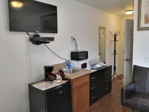 a small kitchen with a sink and a microwave at Apple Inn and Suites Cooperstown Area in Milford