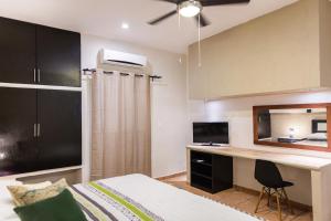 Un dormitorio con una cama y un escritorio con televisión. en Departamento familiar, en Playa del Carmen
