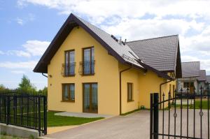 una casa amarilla con techo negro en Sand Residence - Pokoje i Apartamenty, en Władysławowo