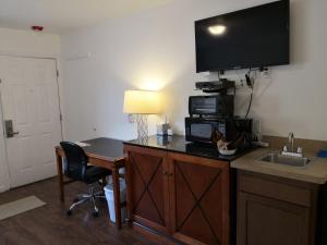 a hotel room with a desk with a microwave and a television at Apple Inn and Suites Cooperstown Area in Milford