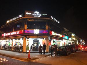 people are standing outside of a restaurant at night at Rest House in Singapore