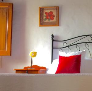 MoyaにあるBELLA DORAMAS Casas Rurales Panchita & Milloのベッドルーム1室(赤い枕とランプ付きのベッド1台付)
