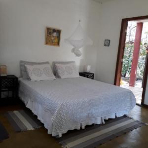 a bedroom with a bed with a white comforter at Casa Coral in Imbassai