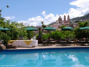 a swimming pool with a table and chairs and a building at Posada de la Mision, Hotel Museo y Jardin in Taxco de Alarcón