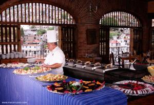 a chef standing in a kitchen with several plates of food at Posada de la Mision, Hotel Museo y Jardin in Taxco de Alarcón