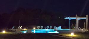 a swimming pool at night with chairs and lights at White Villas in Dhounaíika