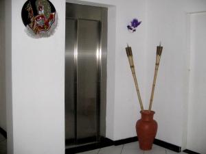 a vase with two sticks in it next to a door at Apart Hotel Marinas Tamandaré in Tamandaré