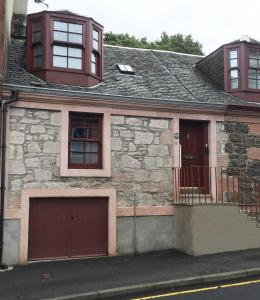 a stone house with a garage and two windows at Old Fisherman's Cottage in Rothesay
