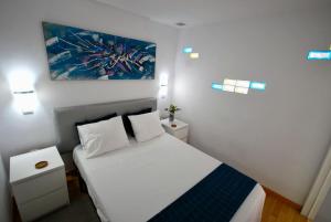 ラスパルマス・デ・グランカナリアにあるCHIC FLAT TRIANAの白いベッドと壁に絵画が飾られたベッドルーム1室