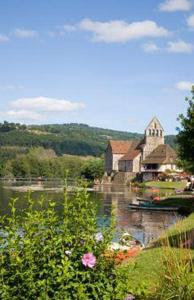 um edifício sobre a água ao lado de um rio com flores em Logis hotel les flots bleus em Beaulieu-sur-Dordogne