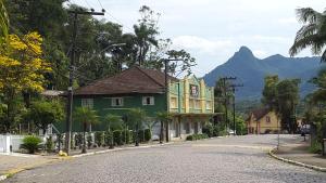 een groen huis op een straat met een berg bij Pousada ECO in Corupá