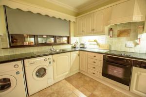a kitchen with white cabinets and a washer and dryer at Rossgier Inn in Lifford