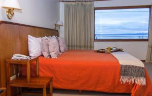 um quarto com uma cama com um cobertor laranja e uma janela em Koi Aiken em El Calafate