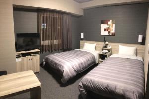 室蘭市にあるホテルルートインGrand室蘭のベッド2台、薄型テレビが備わるホテルルームです。