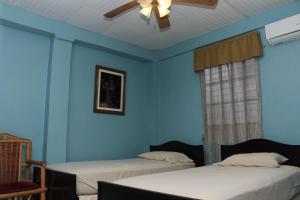 a blue room with two beds and a ceiling fan at Hostel Guayacan in Puerto Armuelles