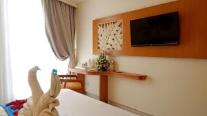 a hotel room with a bed with a tv on the wall at Zia Hotel Kuta in Kuta