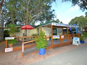 an outdoor cafe with tables, chairs and umbrellas at Riverbend Caravan Park Renmark in Renmark