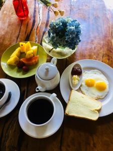 a table with plates of eggs and bread and a cup of coffee at Alam Taman Villa in Tabanan