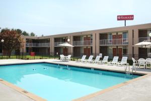 a pool with chairs and umbrellas in front of a hotel at Ramada by Wyndham Wytheville in Wytheville