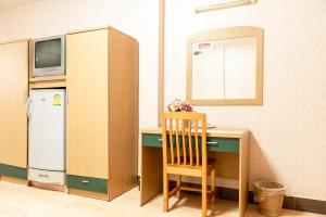 a room with a desk with a refrigerator and a chair at PN Gold Resort in Bangsaen