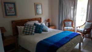 a bedroom with a large bed with a blue blanket at Riverclub Villas in Plettenberg Bay