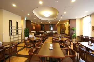a restaurant with wooden tables and chairs and a cafeteria at Hotel Route-Inn Yaizu Inter in Yaizu