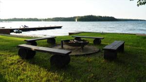 a group of picnic tables and a fire pit next to a lake at Apartamenty Rydzewo in Rydzewo