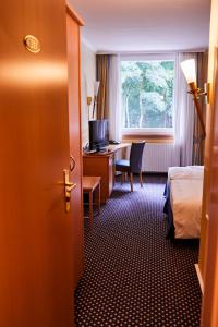 ein Hotelzimmer mit einem Bett, einem Schreibtisch und einem Fenster in der Unterkunft Hotel Cap Polonio in Pinneberg