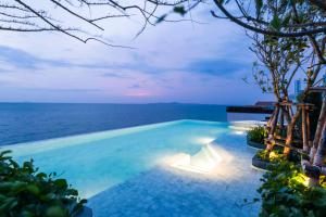 a swimming pool with the ocean in the background at U Jomtien Pattaya in Jomtien Beach