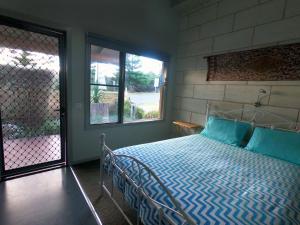 Schlafzimmer mit einem Bett mit blauer Bettwäsche und einem Fenster in der Unterkunft Port Campbell Guesthouse & Flash Packers in Port Campbell