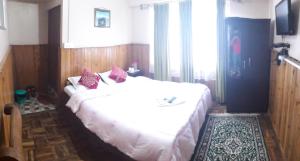 a bedroom with a large white bed with red pillows at White Tara home stay in Darjeeling