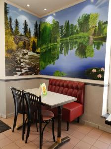een tafel en stoelen in een restaurant met een schilderij aan de muur bij Hôtel Des Vosges in Contrexéville