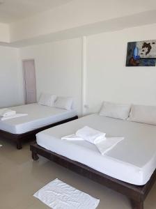 two beds in a room with white walls at Bottle Beach 2 Bungalows in Bottle Beach