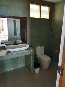 a bathroom with a sink and a toilet and a mirror at Bottle Beach 2 Bungalows in Bottle Beach