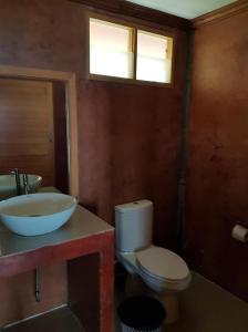 a bathroom with a sink and a toilet and two windows at Bottle Beach 2 Bungalows in Bottle Beach