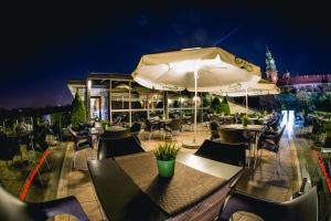 a restaurant with tables and umbrellas at night at Hotel Pod Wawelem in Krakow
