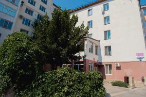 un árbol frente a un edificio blanco en Style Hotel en Lipetsk