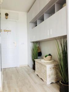 a hallway with white cabinets and a table with plants at Beauté d un jour in Empuriabrava