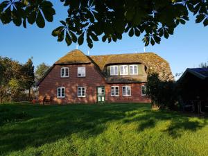 een groot rood bakstenen huis met een rieten dak bij Tammwarftshof in Pellworm