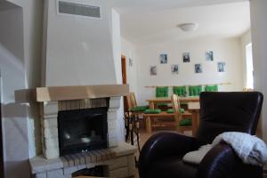 a living room with a fireplace and a chair at Vila Kokrhačka in Loučná pod Klínovcem