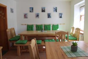 a dining room with a wooden table and green cushions at Vila Kokrhačka in Loučná pod Klínovcem