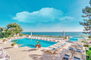 a resort with a pool and chairs and the ocean at Hotel Panorama De Luxe in Odesa